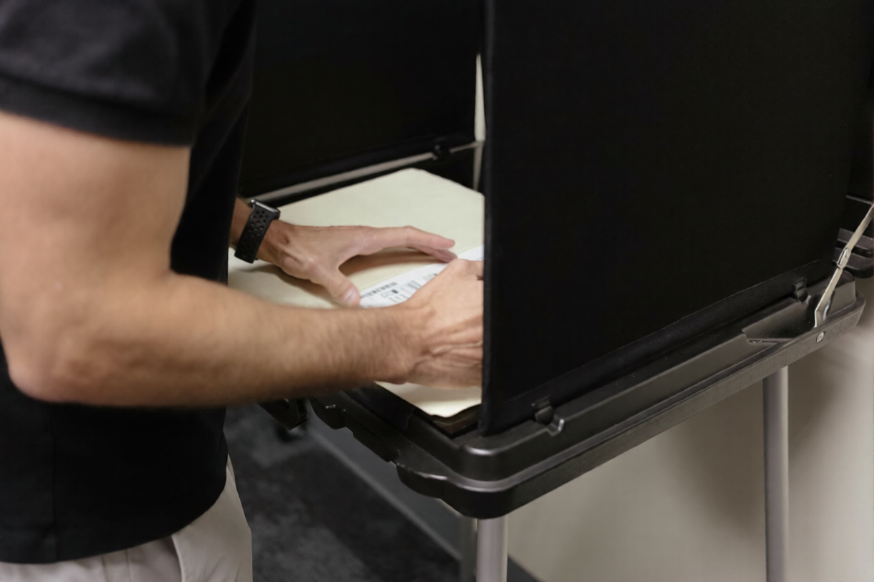 Man casting ballot in voting booth during US election process