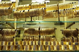 Gold bars and ticker showing downward price movement with Middle East map backdrop