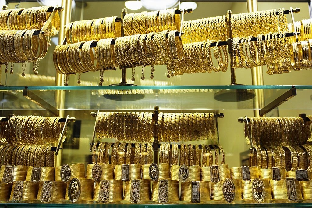 Gold bars and ticker showing downward price movement with Middle East map backdrop