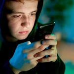 Teenager using smartphone late at night scrolling social media apps