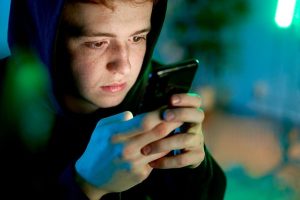 Teenager using smartphone late at night scrolling social media apps