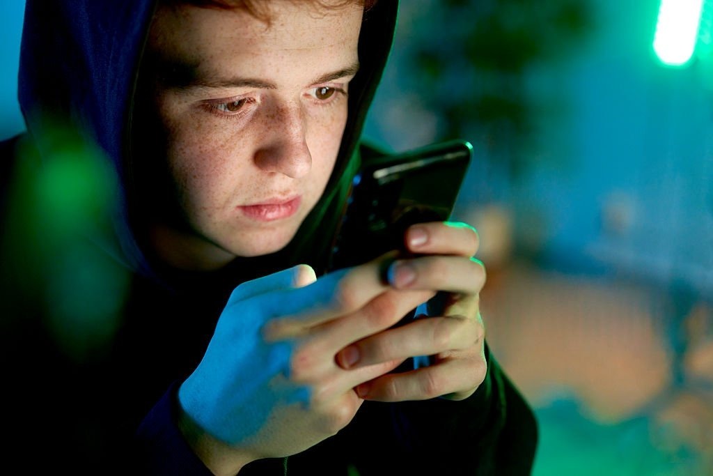Teenager using smartphone late at night scrolling social media apps