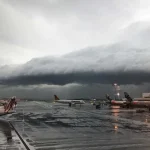 Aircraft grounded at Sydney Airport during severe storm with strong winds and dark clouds
