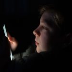 12-year-old boy using smartphone under social media restrictions reflecting EU child online safety and age verification rules
