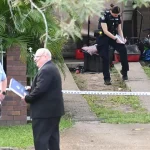 Multiple police vehicles and officers at the scene in Arana Hills, north Brisbane, secured with police tape during a welfare call shooting incident on April 1, 2026.